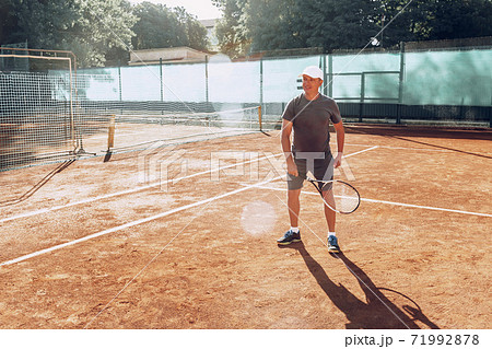 Middle-aged man playing tennis on outdoor tennis filed 71992878