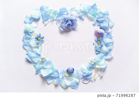 造花の青い花と花びらで模ったハートのフレーム 白いコピースペース 平置きの俯瞰撮影 白バック の写真素材