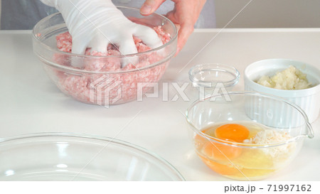 挽き肉に塩胡椒を混ぜてこねる主婦　料理シーン 71997162