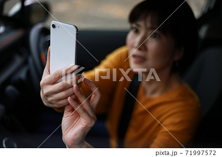 慌ててスマートフォンで撮影する女性 71997572