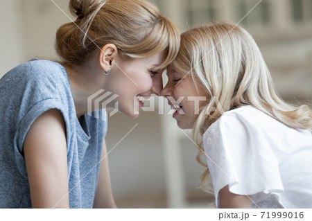 Close up happy laughing mother and little daughter touching foreheads Close up happy laughing mother and little daughter touching foreheads 71999016