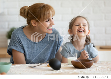 Overjoyed mother and little daughter eating homemade cookies, having fun Overjoyed mother and little daughter eating homemade cookies, having fun 71999024