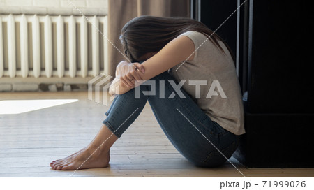 Frustrated unhappy young woman embracing knees, sitting on floor 71999026
