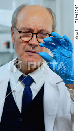Mature man lab technician looking at virus sample 71999246