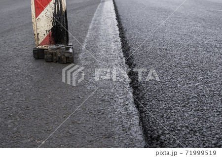A large layer of fresh hot asphalt. Layer of asphalt raw material in a shallow depth of field. Rollers rollin fresh hot asphalt on the new road. Road construction. Construction of a new road. A large layer of fresh hot asphalt. Layer of asphalt raw material in a shallow depth of field. Rollers rollin fresh hot asphalt on the new road. Road construction. Construction of a new road. 71999519