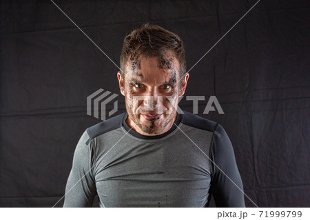 Close-up of a young handsome man with dirty face looks intently at the camera 71999799