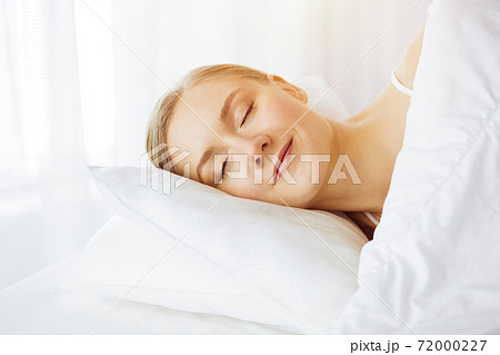 Beautiful young woman sleeping in sunny bedroom comfortably and blissfully. Waking up in fairy morning Beautiful young woman sleeping in sunny bedroom comfortably and blissfully. Waking up in fairy morning 72000227