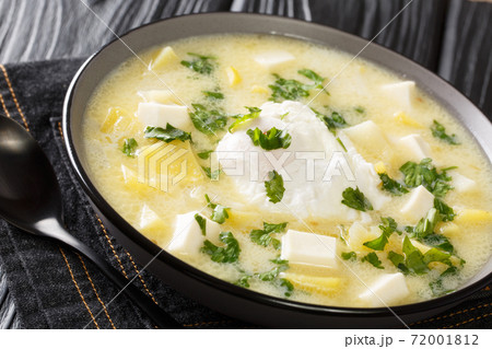 Traditional Venezuelan breakfast of chicken broth, with potatoes, eggs, cheese and cilantro close-up in a bowl. horizontal 72001812