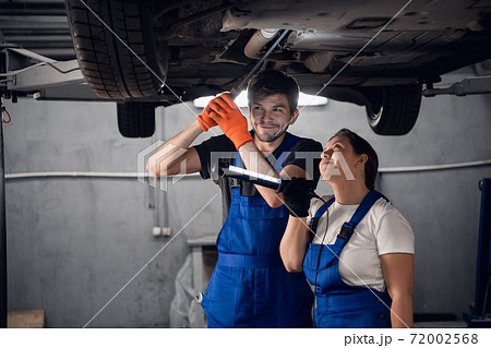 Woman and mechanic inspect car with flashlight 72002568