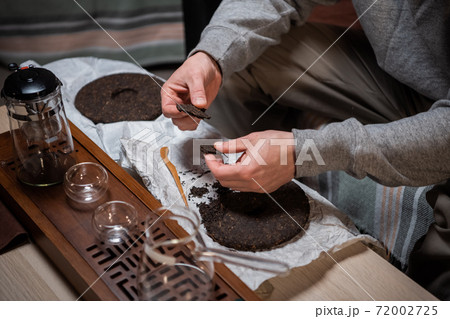 The process of preparing for the tea ceremony is a major one. Men's hands break the tea for brewing in a ceramic teapot to treat their noses. 72002725