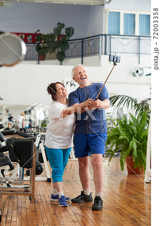 Cheerful senior couple using monopod at gym. Cheerful senior couple using monopod at gym. 72003358