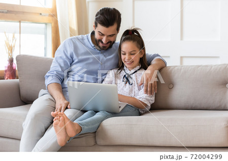 Smiling dad and little daughter using laptop at home Smiling dad and little daughter using laptop at home 72004299