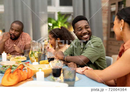 Happy young African man looking at his sister or girlfriend and talking to her Happy young African man looking at his sister or girlfriend and talking to her 72004364