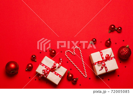 Modern creative minimal solid color holiday composition. Gift box wrapped in craft paper with red ribbon bow with copyspace on red background 72005085