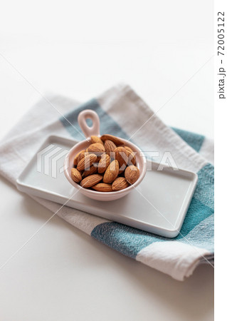 Fresh raw nuts in a pink bowl on a towel on a gray table, vertical photo 72005122