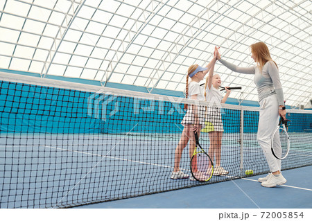 Happy preteenage girls in activewear giving high five to their tennis trainer Happy preteenage girls in activewear giving high five to their tennis trainer 72005854