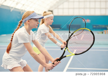 Two teenage girls in activewear standing on stadium with legs bent in knees 72005908
