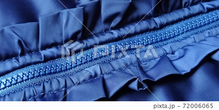Buttoned zip on a blue raincoat. Waves and folds in the fabric. Beautiful flounces, ruffles, frills. Decorative finishing of a garment. Smocked, sewn silk fabric. Nice casual wear. 72006065