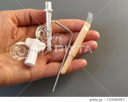 Transparent plastic bobbins from a modern sewing machine in the palm of a woman - seamstresses, needles, thread take-up, whipping tool. Gray background. sewing machines 72006067
