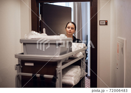 A hotel housekeeper pushing a cleaning supply cart A hotel housekeeper pushing a cleaning supply cart 72006483