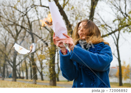 Woman hold burning paper with flying ash 72006892