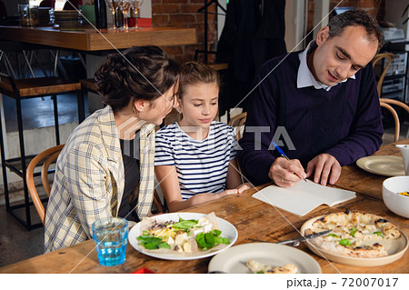 Young parents checking their daughter's homework. There are a few things to correct. 72007017