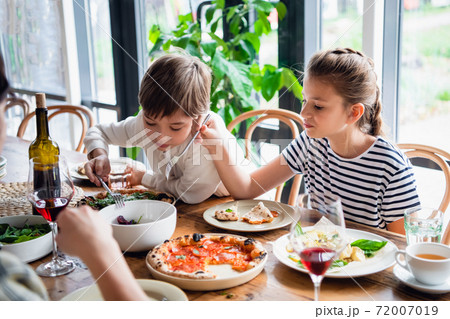 Two beautiful kids eating with a appetite 72007019