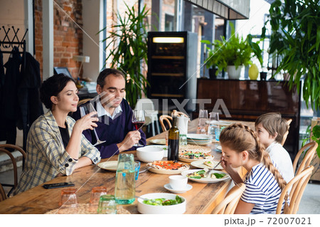 A family of four having a dinner in a cafe 72007021