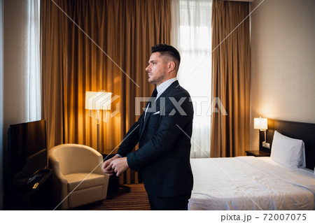Young handsome businessman adjusting his jacket, dressing up at 72007075
