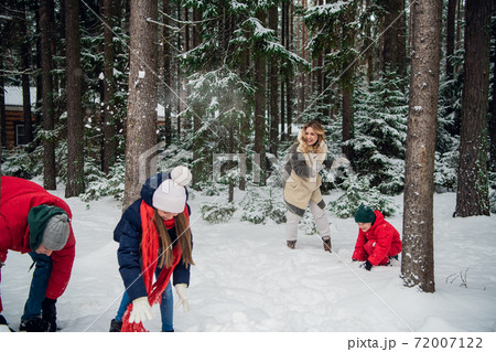 A large family walks in the woods in winter and throws snowballs at each other A large family walks in the woods in winter and throws snowballs at each other 72007122