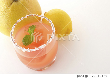 グラスの縁に塩が付いているミント入りのピンクソルティドッグとグレープフルーツとレモンを白背景で撮影 72010189