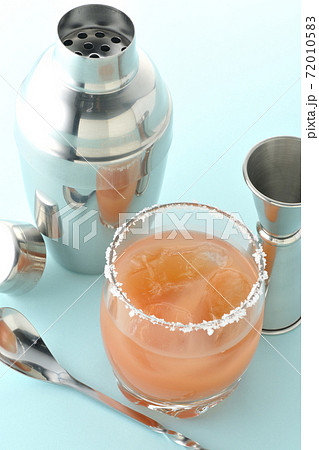 グラスの縁に塩が付いているピンクソルティドッグとカクテルシェーカーとメジャーカップ グラスの縁に塩が付いているピンクソルティドッグとカクテルシェーカーとメジャーカップ 72010583