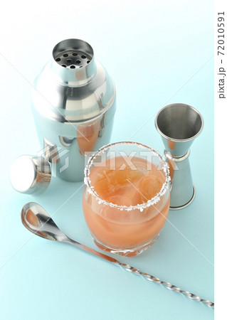 グラスの縁に塩が付いているピンクソルティドッグとカクテルシェーカーとメジャーカップ グラスの縁に塩が付いているピンクソルティドッグとカクテルシェーカーとメジャーカップ 72010591