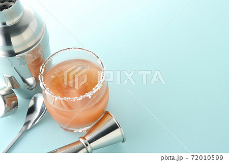 グラスの縁に塩が付いているピンクソルティドッグとカクテルシェーカーとメジャーカップ グラスの縁に塩が付いているピンクソルティドッグとカクテルシェーカーとメジャーカップ 72010599