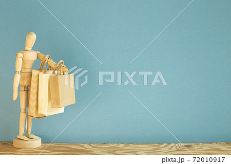 Wooden mannequin doll holding paper shopping bags. blue background 72010917