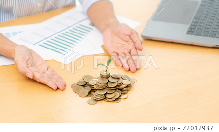 Hands of businessman putting coin into plant sprouting growing up to profit, demonstrating financial growth through saving plans and investment schemes. 72012937