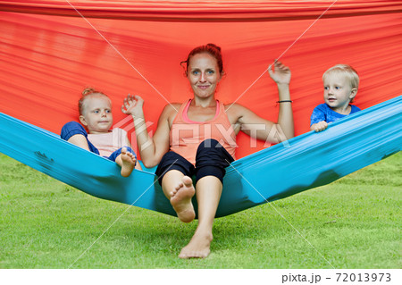 Funny kids with young mother chilling in swinging hammock 72013973