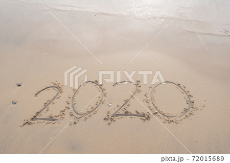 Sea wave wipe away 2020 Text writing on white sand Tropical beach in the morning Beautiful light sunrise on beach and wave crashing on sandy shore. 72015689