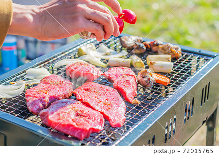 屋外のオープングリルで牛肉を網焼きしている様子 72015765