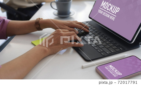 Hands typing on tablet keyboard on meeting table with smartphone 72017791