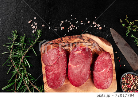 Gourmet meat. Beef steaks on a cutting board with seasoning and copy space Gourmet meat. Beef steaks on a cutting board with seasoning and copy space 72017794