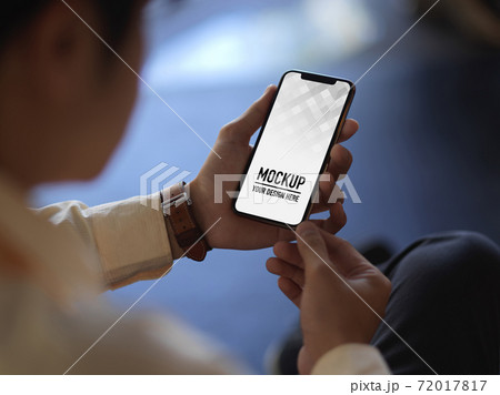 Cropped shot of businessman hands holding smartphone while relaxed sitting in office room Cropped shot of businessman hands holding smartphone while relaxed sitting in office room 72017817