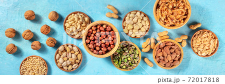 Nuts panorama on a vibrant blue background. A selection of various nuts Nuts panorama on a vibrant blue background. A selection of various nuts 72017818