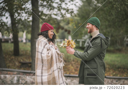 Man brings a bunch of yellow leaves to his girlfriend Man brings a bunch of yellow leaves to his girlfriend 72020223