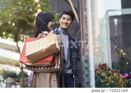 happy young asian couple walking on street in the city with shopping bags in hands happy young asian couple walking on street in the city with shopping bags in hands 72022169