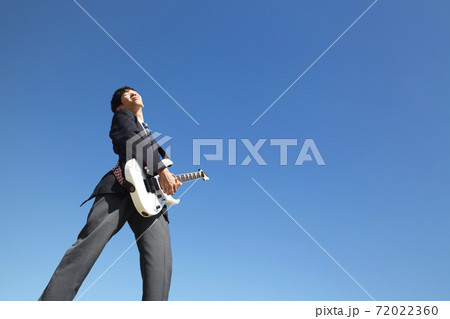 青空を背景に屋外でエレキギターを演奏する男子高校生 青空を背景に屋外でエレキギターを演奏する男子高校生 72022360