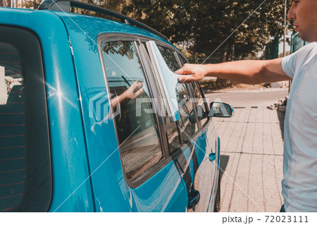 cleaning the car glass, a man wipes excess water from the glass in the car. cleaning the car glass, a man wipes excess water from the glass in the car. 72023111