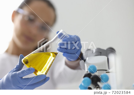 Researcher holds flask with yellow liquid closeup 72023584
