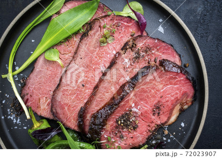 Traditional barbecue dry aged sliced angus roast beef steak with wild garlic and fruits 72023907
