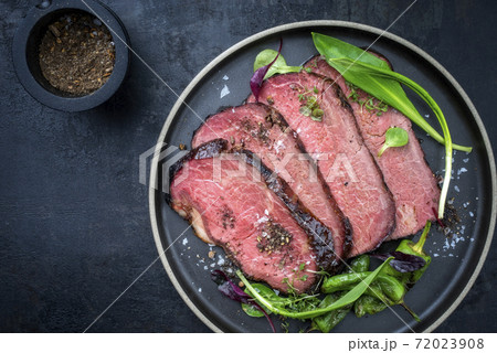 Traditional barbecue dry aged sliced angus roast beef steak with wild garlic and fruits 72023908